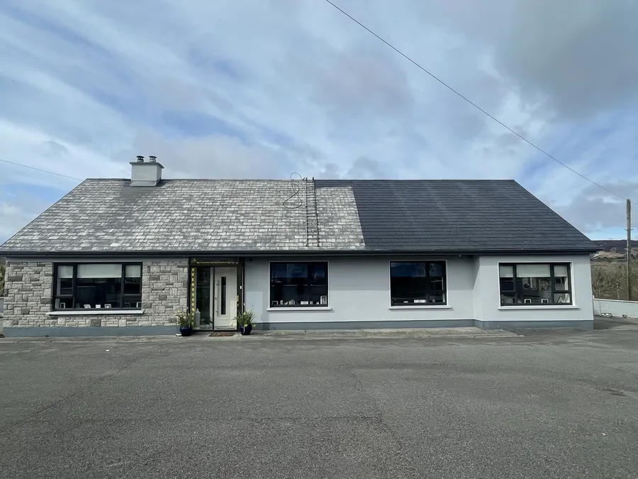 Stone-fronted bungalow with half its roof cleaned and re-coloured beside the weathered old finish, Flaherty Roof and Driveways