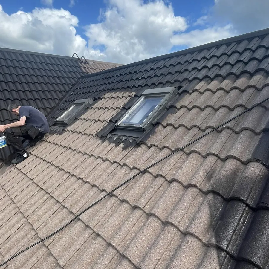 Roofer re-colouring tiles around a roof window, Flaherty Roof and Driveways